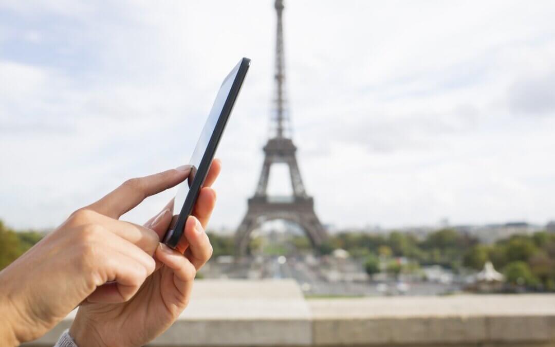 femme utilisant son telephone portable devant la tour eiffel