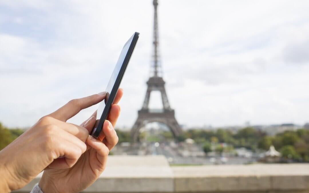 femme utilisant son telephone portable devant la tour eiffel